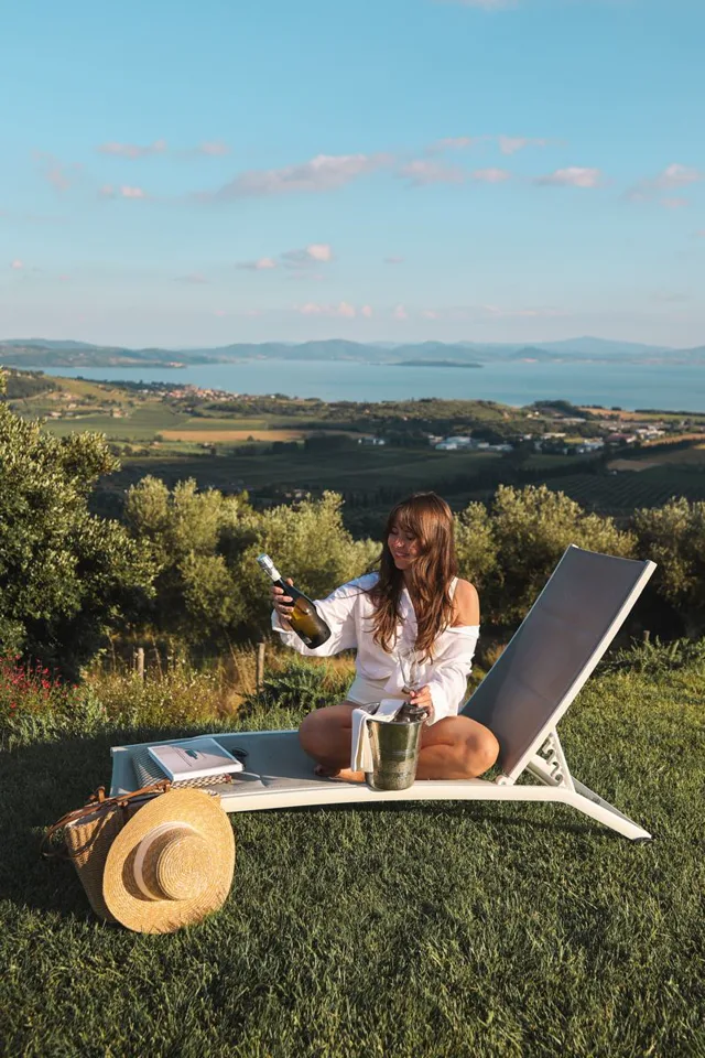 Thessa on her phone on a sun lounger with a view over the lake